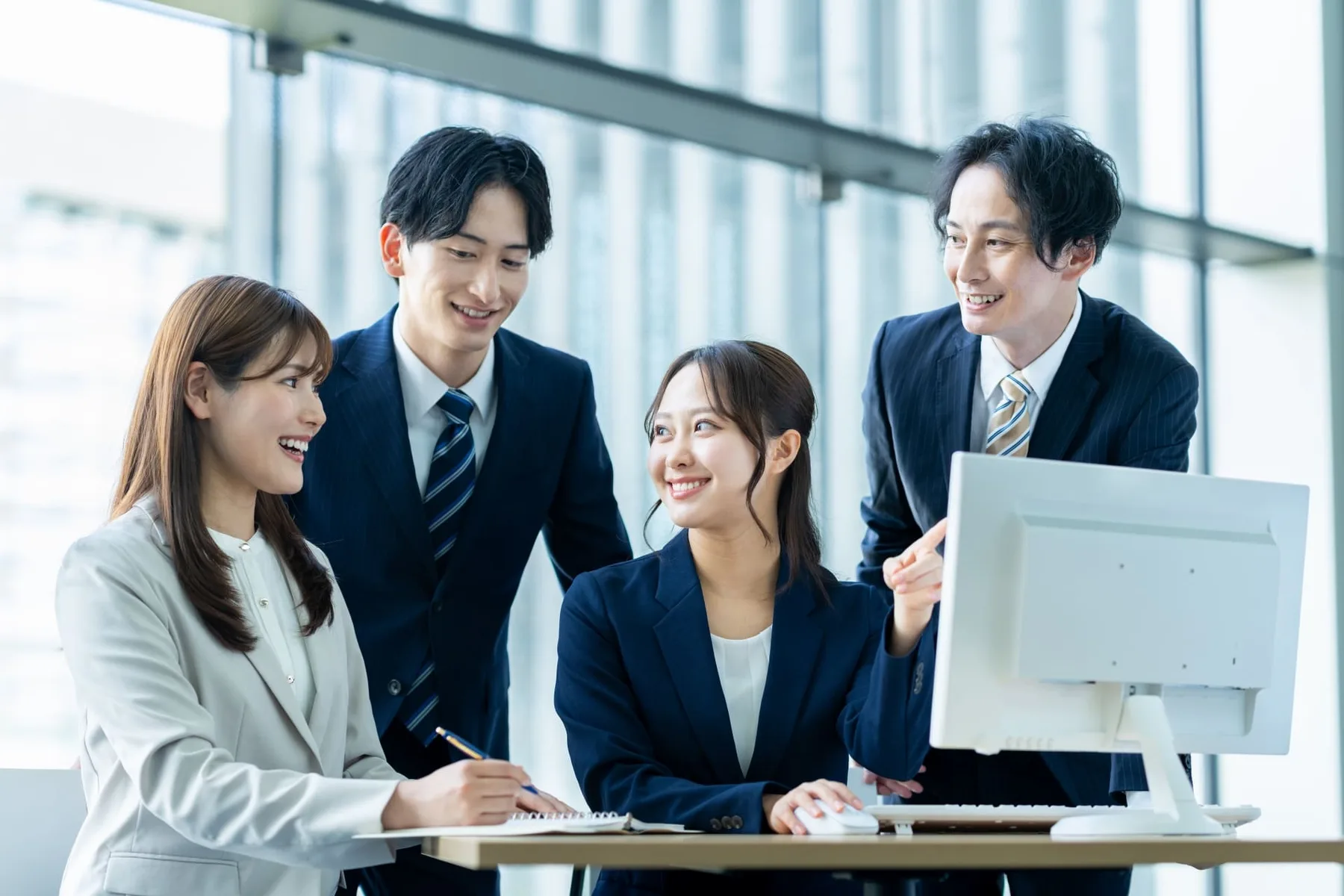 サイトの画面を見ながら笑顔で話すチームのイメージ